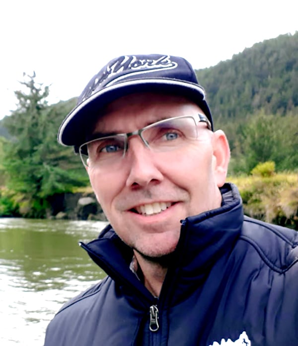 Mike Reimer poses in front of a river in the mountains.